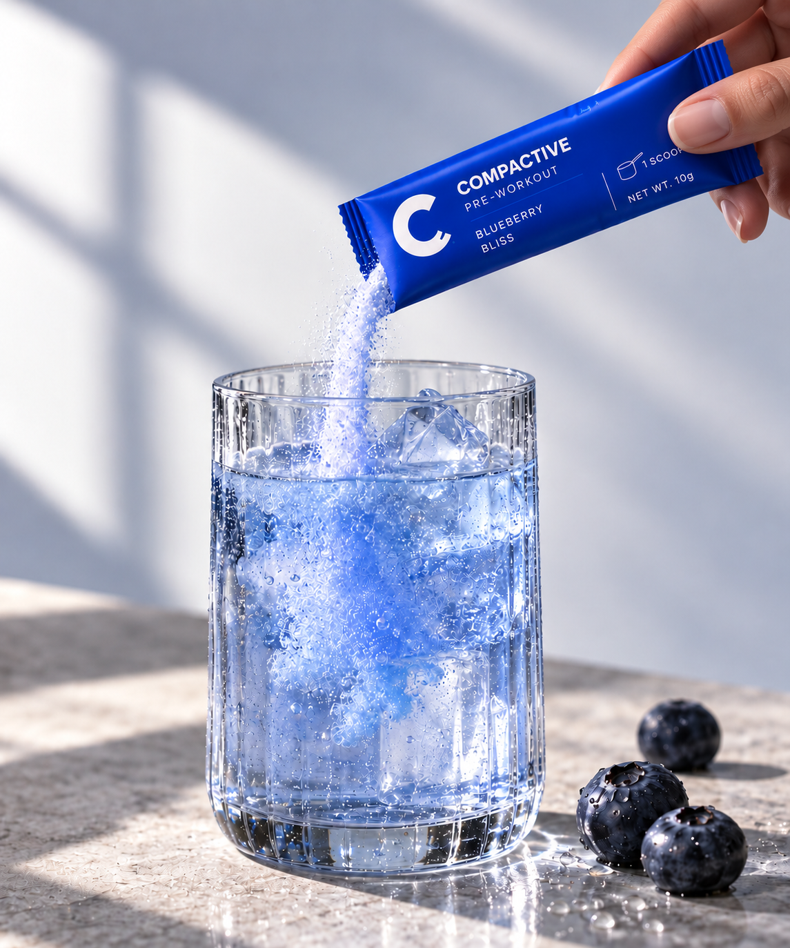 Compactive Blueberry Bliss pre-workout sachet being poured into a glass of iced water